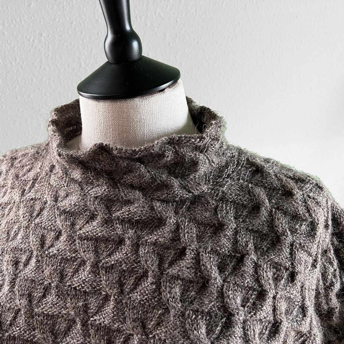 Detail of grey knitted sweater with texture pattern and funnel neck
